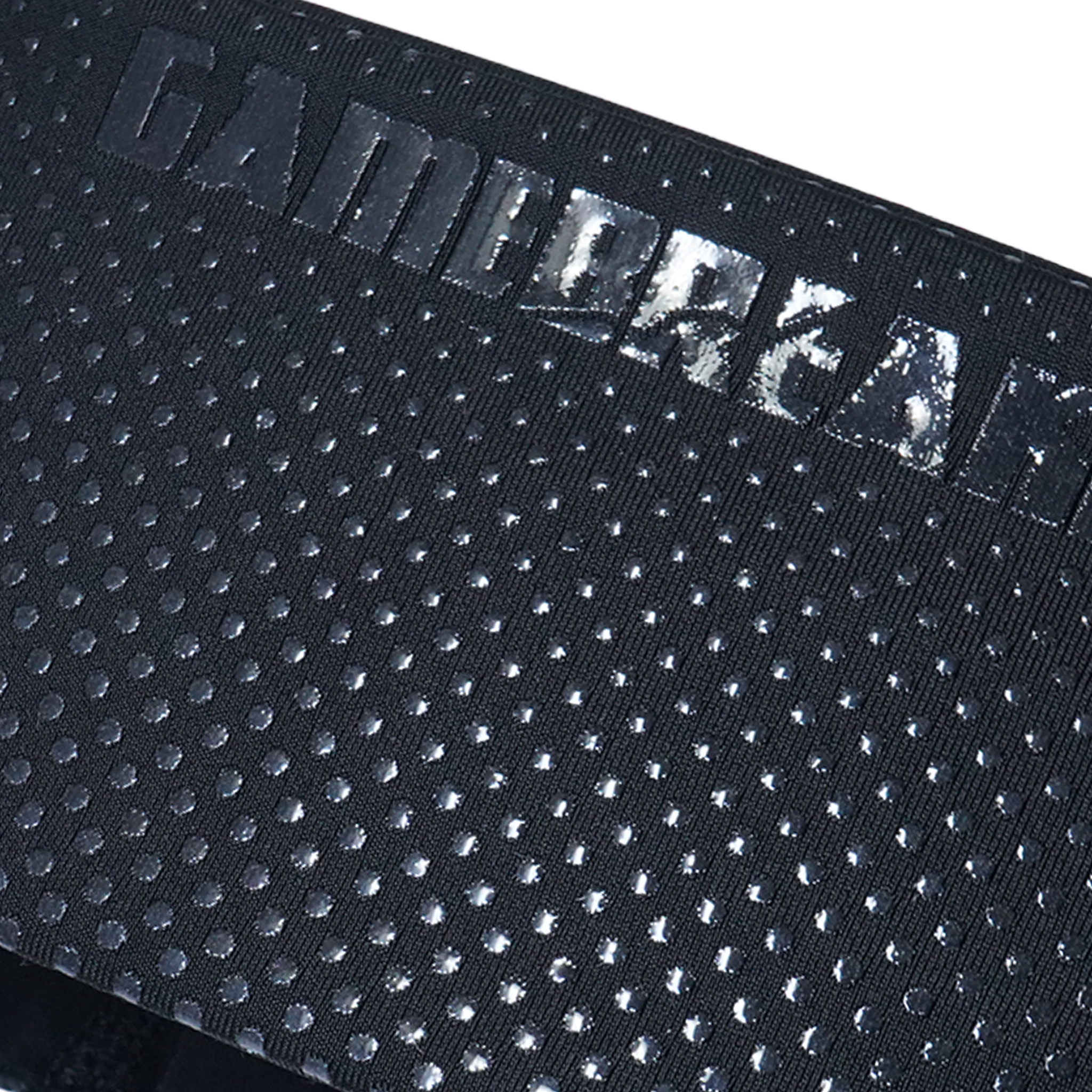 Close-up of a black textured fabric strap with a repeating circular dot pattern and a debossed metallic logo reading 'GAMEBREAKER' across the top edge.