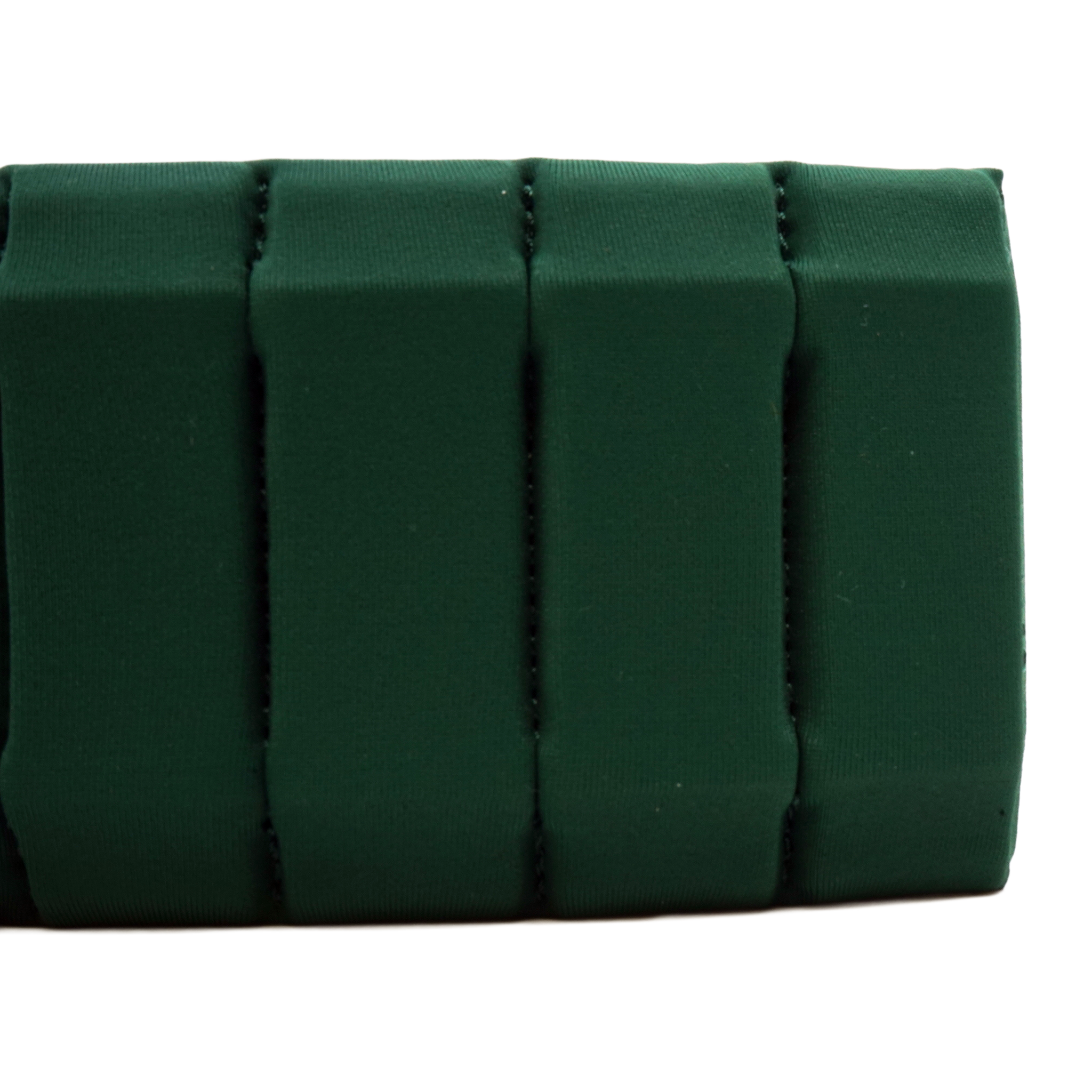 A close-up of a dark forest green fabric accessory, showing a textured surface with vertical stitched channels, on a plain white background.