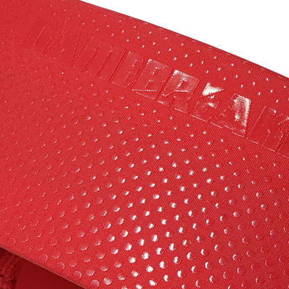 Close-up of a red textured surface with a repeating small dot pattern and a glossy embossed brand mark reading 'GAMEBREAKER' across the top.