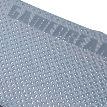 Close-up of a gray textured gaming mat with a raised 'GAMEBREAKER' logo and a uniform raised-dot pattern, shown against a white background.