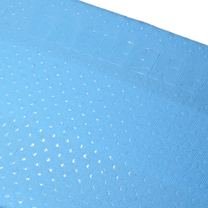 A close-up of a light blue textured fabric with a repeating pattern of small white embroidered dots and a stitched border along the top edge.